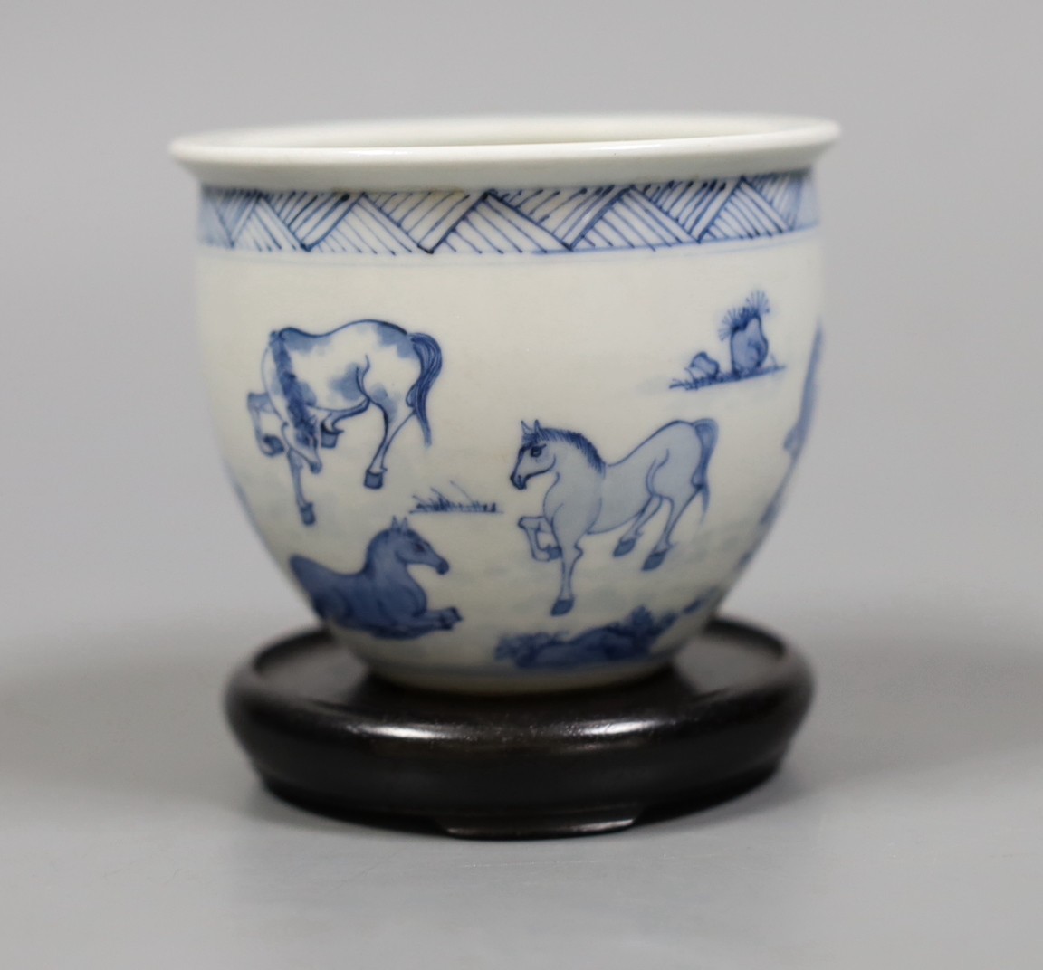 A Chinese blue and white ‘eight horses’ brush pot, on wooden stand, 8cm tall including stand